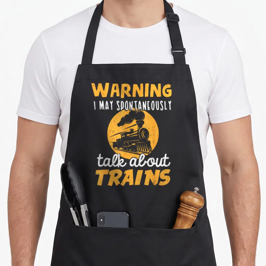 Warning talk about apron - Distressed orange circle with grey steam train and warning text — shown on a black cotton canvas apron against a white background