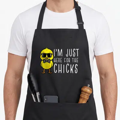 Toddler easter apron - Cartoon yellow chick with sunglasses and text I'M JUST HERE FOR THE CHICKS — shown on a black cotton canvas apron against a white background