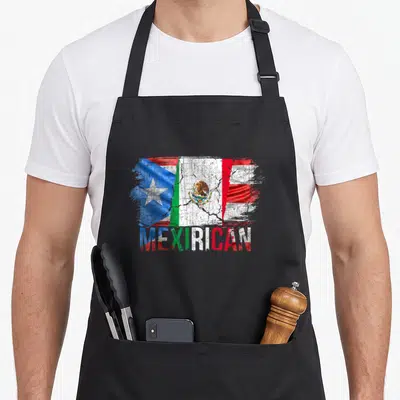 Mexirican mexico apron - Blurred red white blue green flags merging above distressed MEXIRICAN text filled — shown on a black cotton canvas apron against a white background