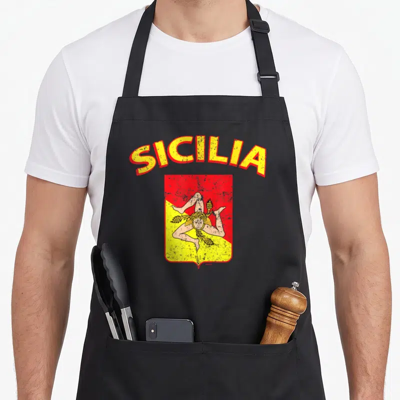 Italia sicily apron - Retro triskelion shield with arched SICILIA text in yellow and red — shown on a black cotton canvas apron against a white background