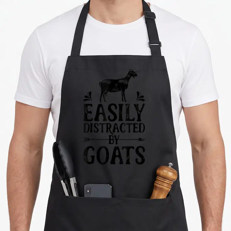 Easily farmers apron - Black goat silhouette above distressed text reading Easily Distracted By Goats with arrow details — shown on a black cotton canvas apron against a white background