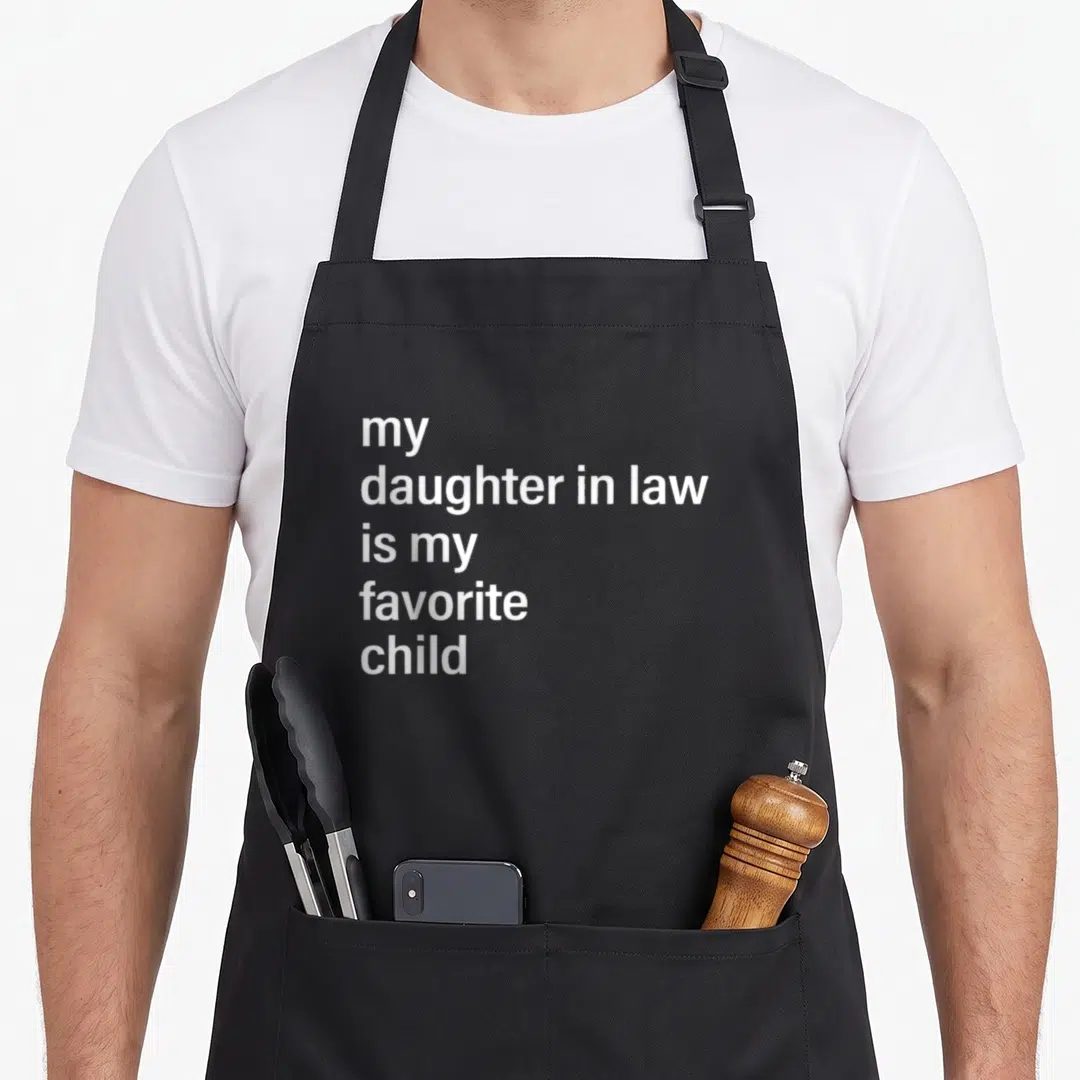 Law father mom and daughter aprons - white text reading my daughter in law is my favorite child on black fabric — shown on a black cotton canvas apron against a white background