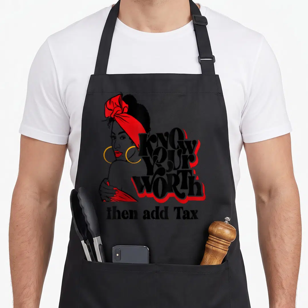 Afro tax apron - Cartoon woman with red headwrap and gold hoops next to KNOW YOUR WORTH then add Tax text — shown on a black cotton canvas apron against a white background