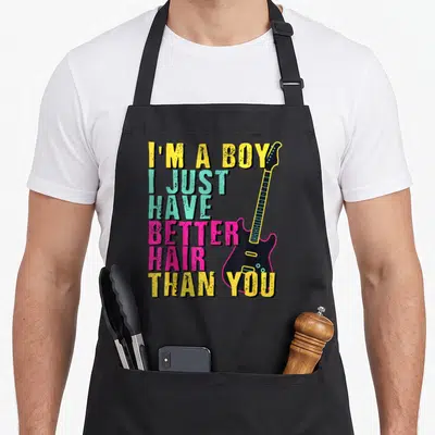 Toddler hair apron - Stacked colorful text I'M A BOY next to a vertical black electric guitar with cyan dots — shown on a black cotton canvas apron against a white background