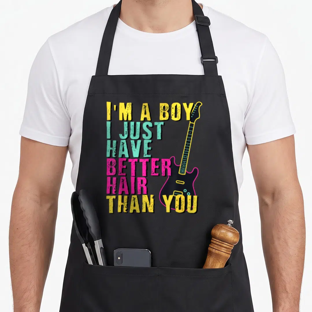 Toddler hair apron - Stacked colorful text I'M A BOY next to a vertical black electric guitar with cyan dots — shown on a black cotton canvas apron against a white background