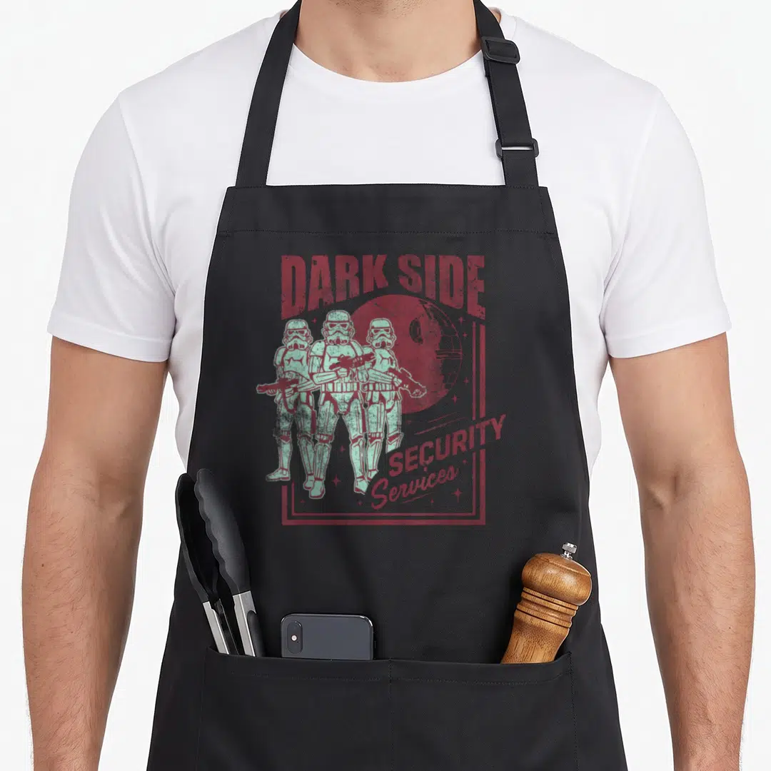 Dark service apron - Three mint green Stormtroopers with red DARK SIDE SECURITY Services text and Death Star background — shown on a black cotton canvas apron against a white background