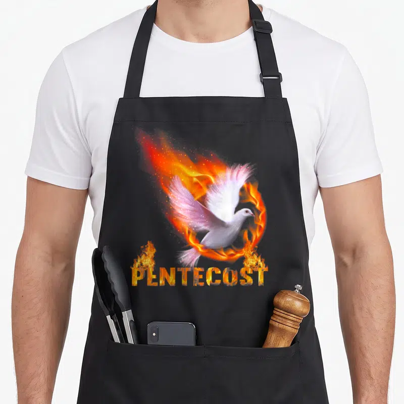 Pentecost catholic apron - White dove surrounded by fire ring with flame-textured PENTECOST lettering below — shown on a black cotton canvas apron against a white background