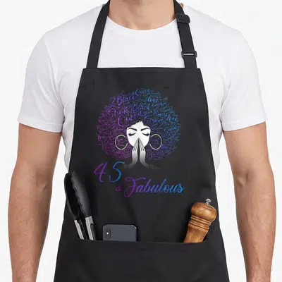 Afro hair apron - 45 & Fabulous text under woman with word-art afro in purple and blue — shown on a black cotton canvas apron against a white background