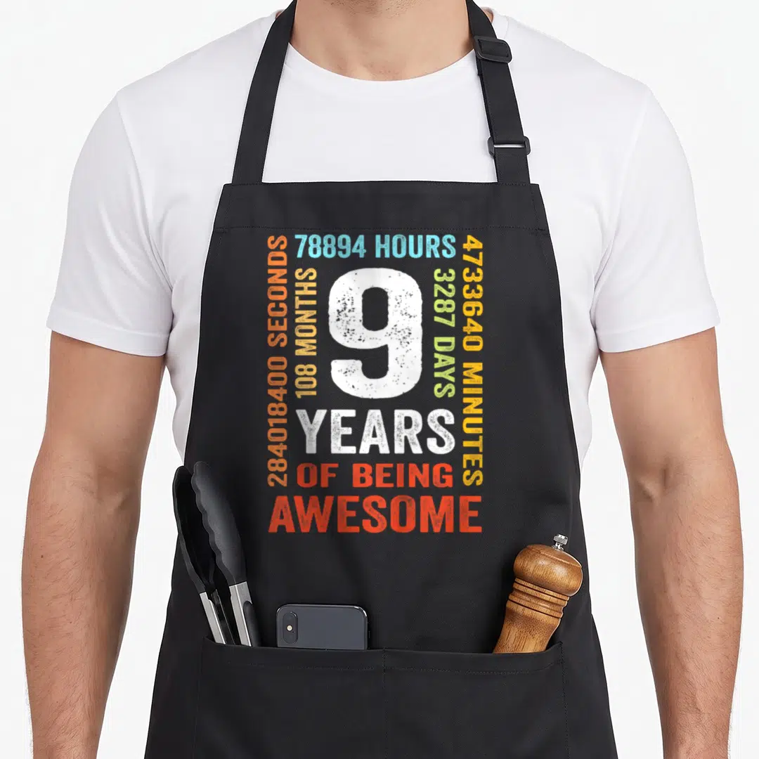 9th birthday apron - Distressed white number 9 surrounded by colorful time measurements and 9 years of being awesome — shown on a black cotton canvas apron against a white background