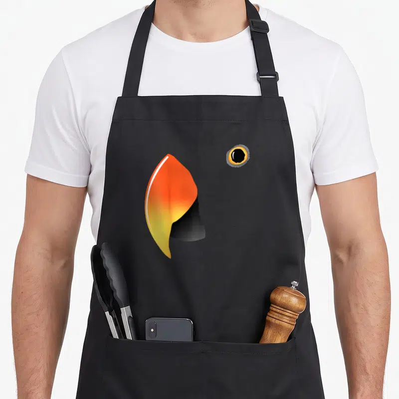 Eclectus parrot bird apron - Orange yellow black bird beak and eye minimalist print — shown on a black cotton canvas apron against a white background