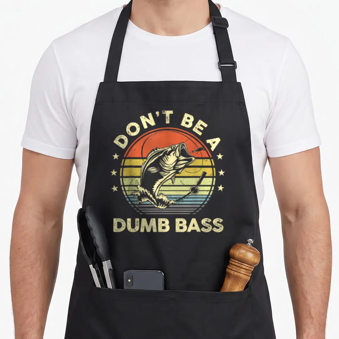Bass fish fishing aprons - Retro sun with jumping bass fish, fishing rod, and text Don't Be A Dumb Bass — shown on a black cotton canvas apron against a white background