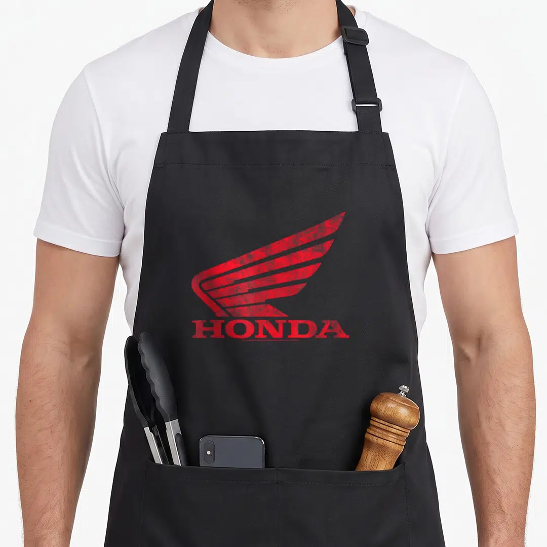 Honda distressed apron - Red distressed wing logo above HONDA text with small watermark below — shown on a black cotton canvas apron against a white background