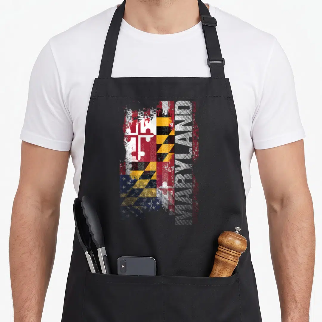 State maryland apron - Distressed Maryland flag design with vertical MARYLAND text in red white yellow and black — shown on a black cotton canvas apron against a white background
