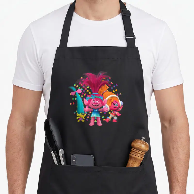 Roll troll apron - Three cartoon trolls clustered with pink blue and orange confetti — shown on a black cotton canvas apron against a white background