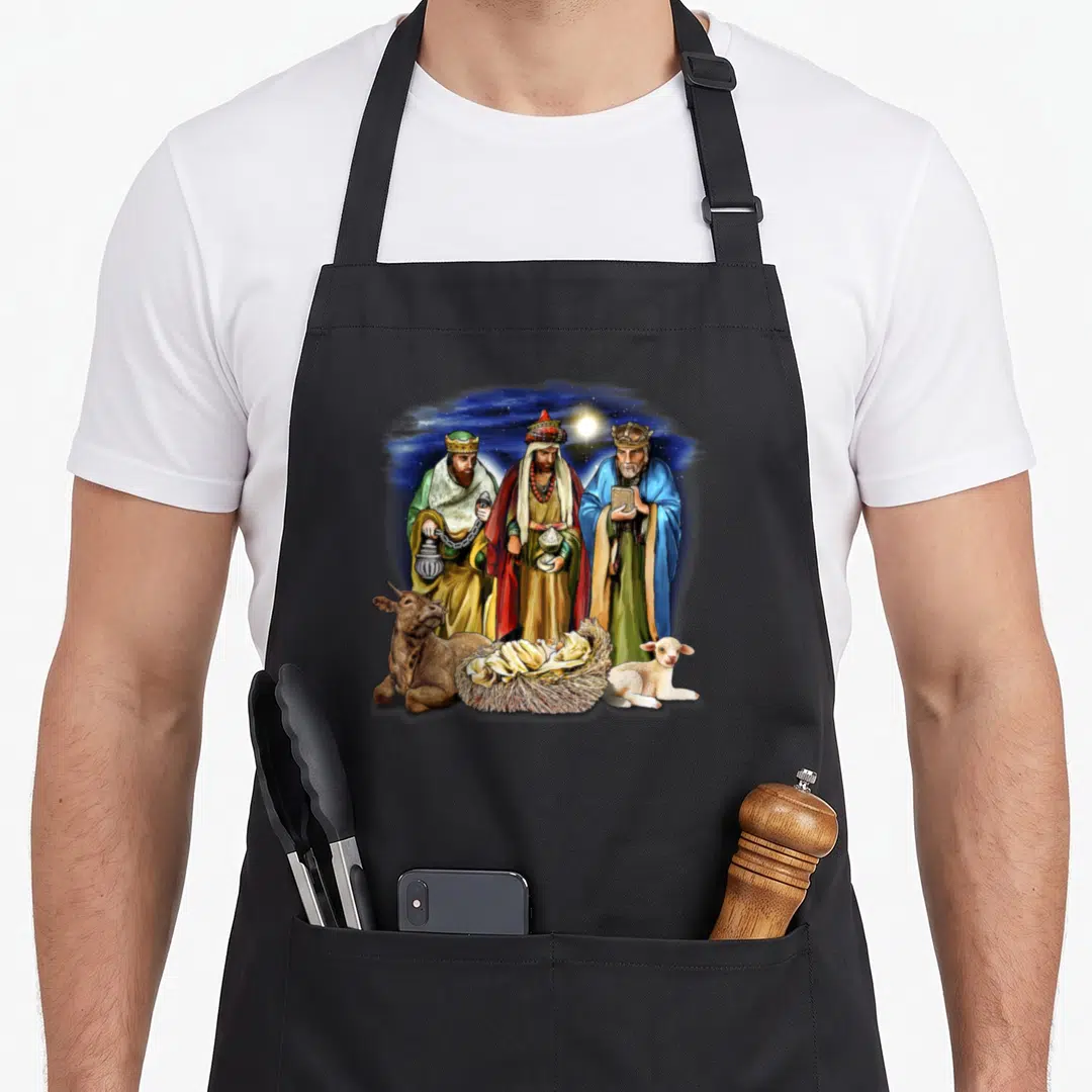 King womens christmas apron - Three wise men and baby in manger with cow lamb and star in blue red green gold — shown on a black cotton canvas apron against a white background