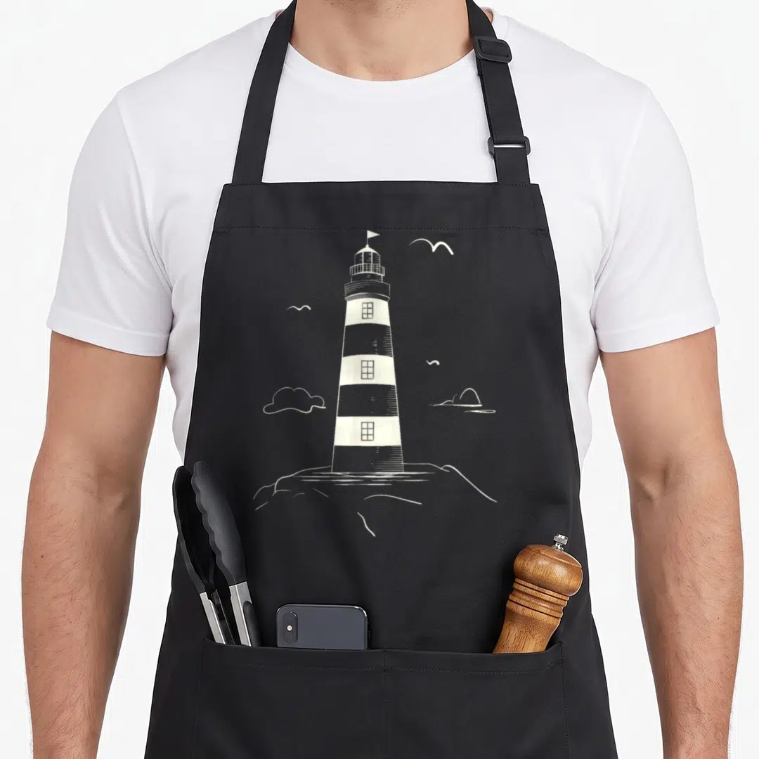 Lighthouse collection apron - White line-art lighthouse on a rock with clouds and birds in the sky — shown on a black cotton canvas apron against a white background