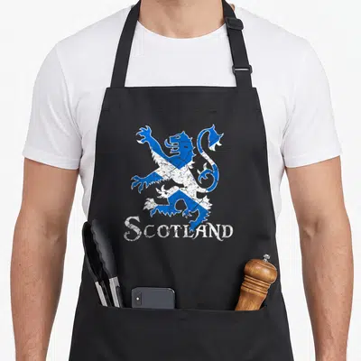 Scotland lion apron - Distressed blue and white lion rampant filled with saltire pattern above SCOTLAND text — shown on a black cotton canvas apron against a white background