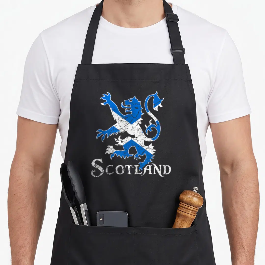 Scotland lion apron - Distressed blue and white lion rampant filled with saltire pattern above SCOTLAND text — shown on a black cotton canvas apron against a white background