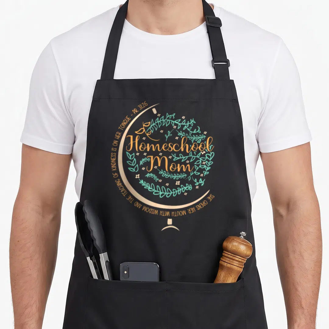 Funny homeschool christian apron - Peach globe with teal leaves and white flowers enclosing Homeschool Mom text — shown on a black cotton canvas apron against a white background