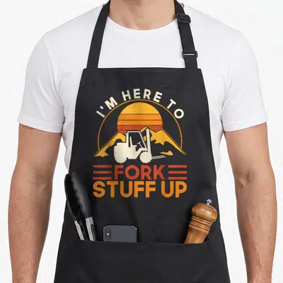 Driver fork apron - Retro forklift graphic with orange mountains and I'M HERE TO FORK STUFF UP text — shown on a black cotton canvas apron against a white background