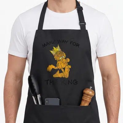 Way cat apron - Garfield in yellow crown with Make Way for the King text in orange and black — shown on a black cotton canvas apron against a white background