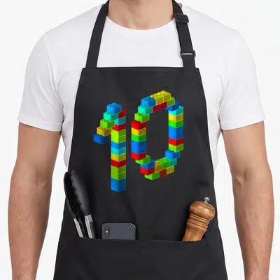 Block 10th building aprons - Number 10 formed by multicolored interlocking toy bricks in red blue yellow and green — shown on a black cotton canvas apron against a white background