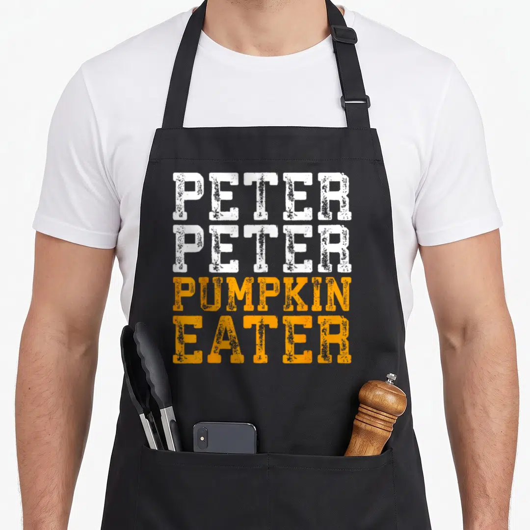 Peter pumpkin apron - Stacked distressed text reading PETER PETER PUMPKIN EATER in white and orange — shown on a black cotton canvas apron against a white background