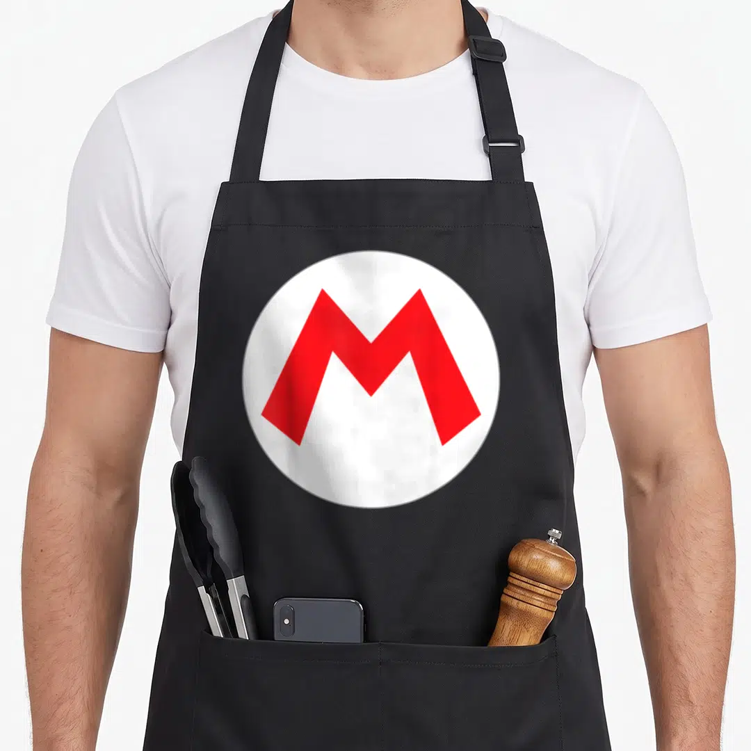 Icon costume apron - Red letter M centered in a white circle on black fabric — shown on a black cotton canvas apron against a white background