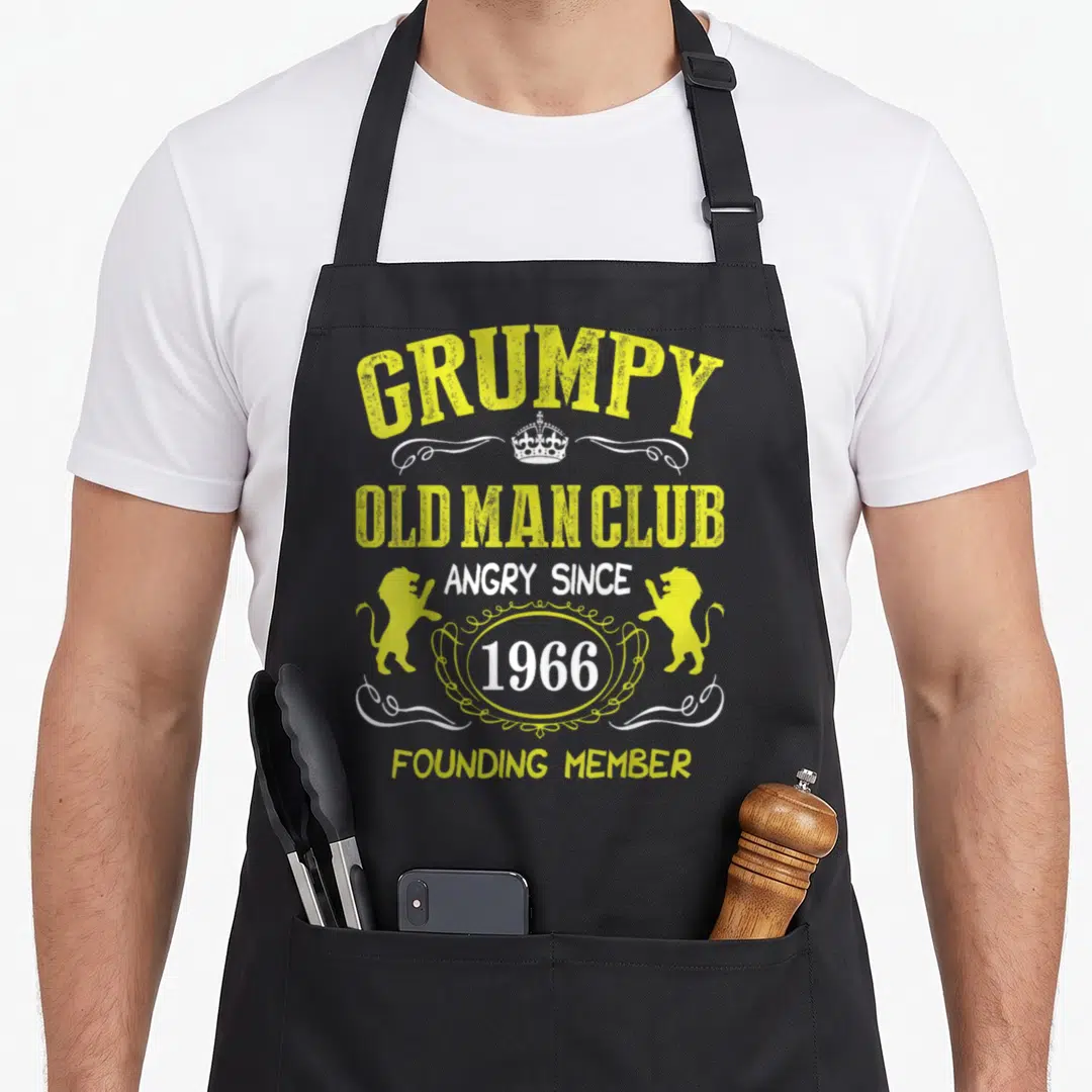 Grumpy founder apron - Yellow and white text reading Grumpy Old Man Club 1966 Founding Member with two lions and crown — shown on a black cotton canvas apron against a white background