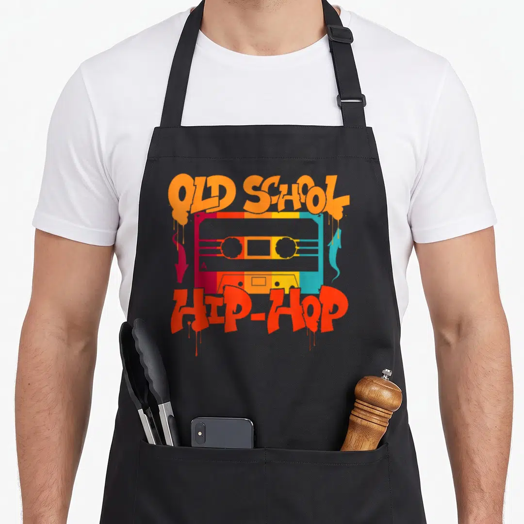 School hip apron - Retro cassette tape graphic with dripping orange and red graffiti text reading OLD SCHOOL A HIP-HOP — shown on a black cotton canvas apron against a white background