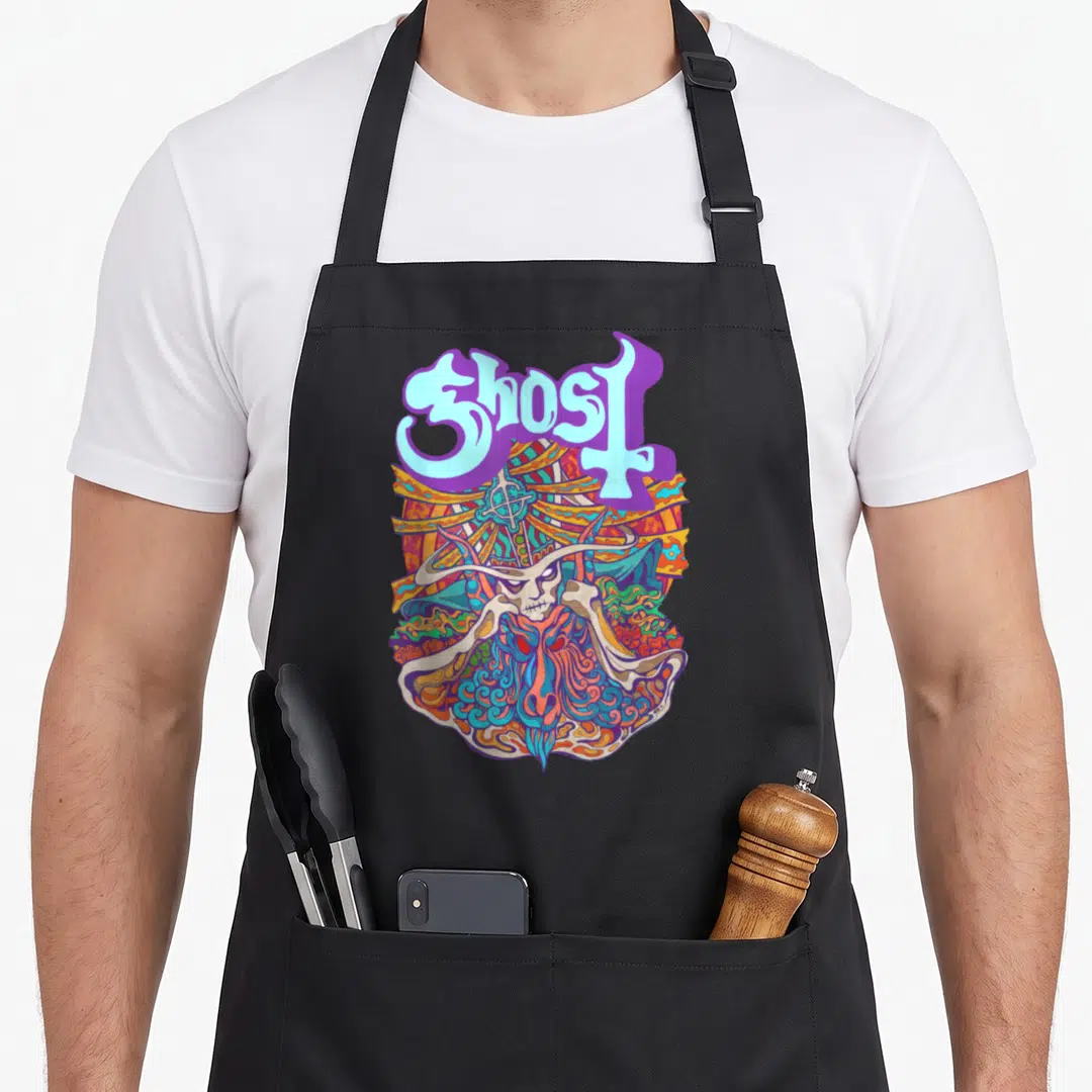 Seven ghost apron - Stylized Ghost text above a colorful horned demon head with a cross in purple and orange cartoon art — shown on a black cotton canvas apron against a white background