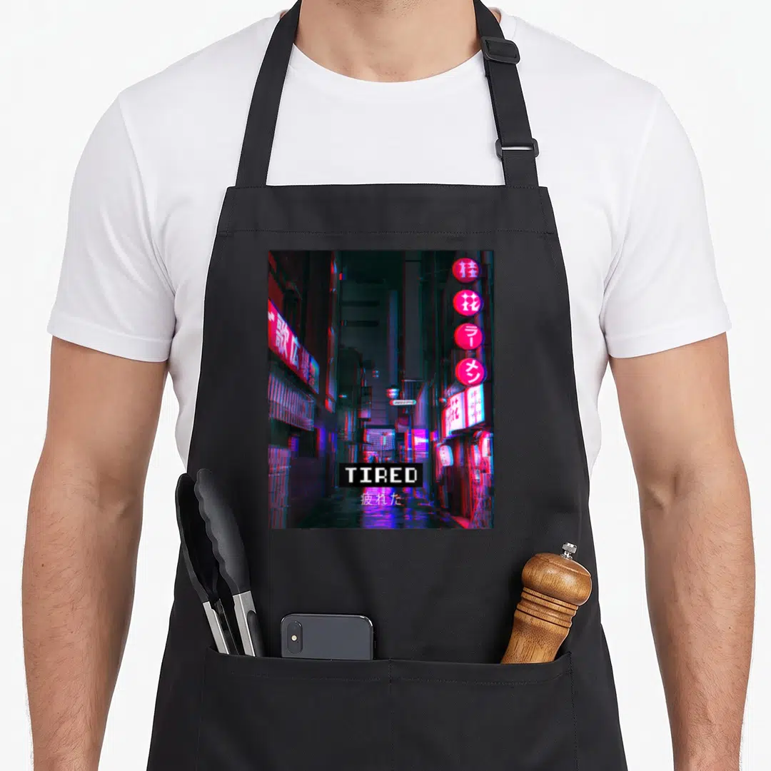 Tired vaporwave apron - Neon alleyway photo with TIRED text and Japanese characters centered at bottom — shown on a black cotton canvas apron against a white background