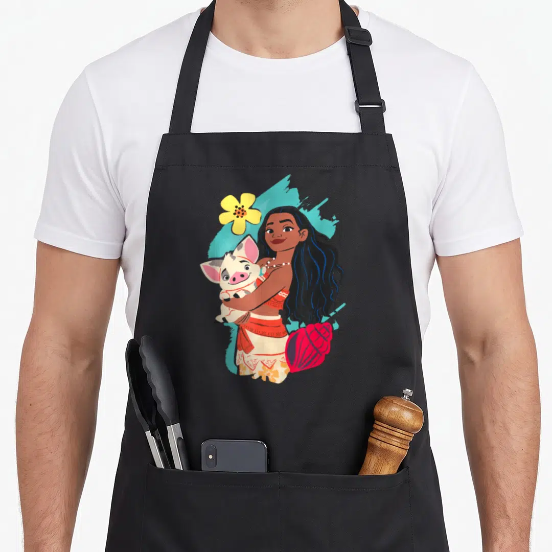 Pua princess apron - Moana holding a pig with yellow flower and red shell on blue background — shown on a black cotton canvas apron against a white background