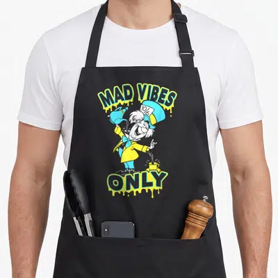 Hatter alice wonderland apron - Mad Hatter cartoon holding teapot and cup with Mad Vibes Only text in yellow blue white — shown on a black cotton canvas apron against a white background