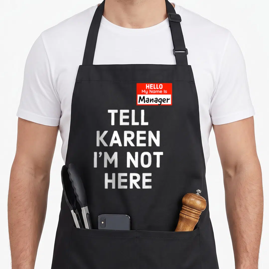 Minute halloween apron - Red name tag reading Manager with stacked white text TELL KAREN I'M NOT HERE — shown on a black cotton canvas apron against a white background