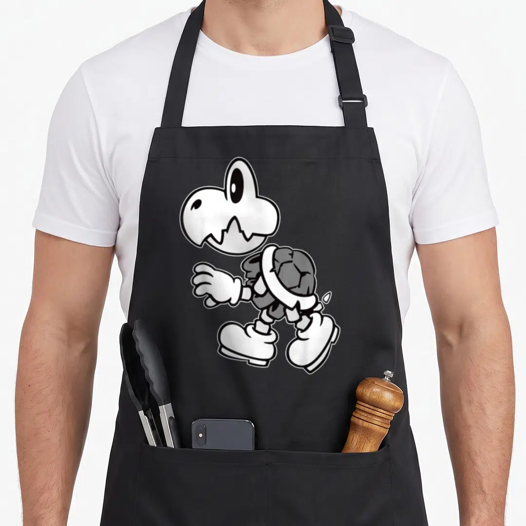 Dry holiday apron - Cartoon skeleton with cracked shell, white shoes, and detached skull in grey and black — shown on a black cotton canvas apron against a white background