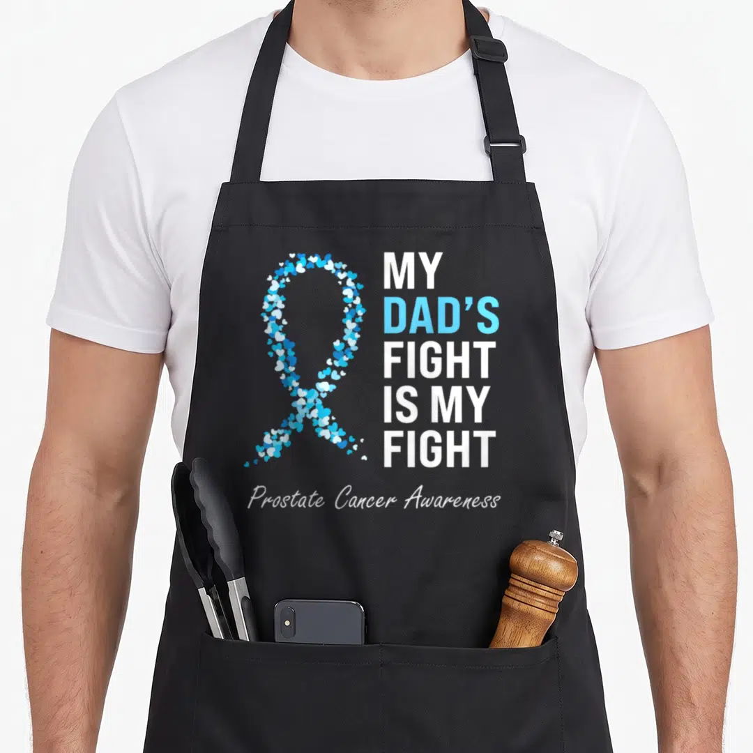 Light ribbon apron - Blue and white heart-shaped awareness ribbon next to stacked text reading My Dad's Fight Is My — shown on a black cotton canvas apron against a white background