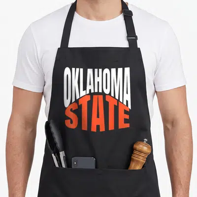 State oklahoma girl apron - White and orange typography reading OKLAHOMA STATE stacked vertically — shown on a black cotton canvas apron against a white background