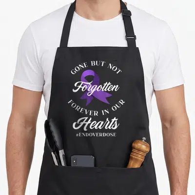 End recovery day apron - Purple ribbon with white text Gone But Not Forgotten Forever In Our Hearts EndOverdose — shown on a black cotton canvas apron against a white background