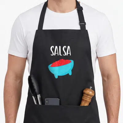 Salsa friends apron - White SALSA text above a blue bowl filled with red salsa in cartoon style — shown on a black cotton canvas apron against a white background