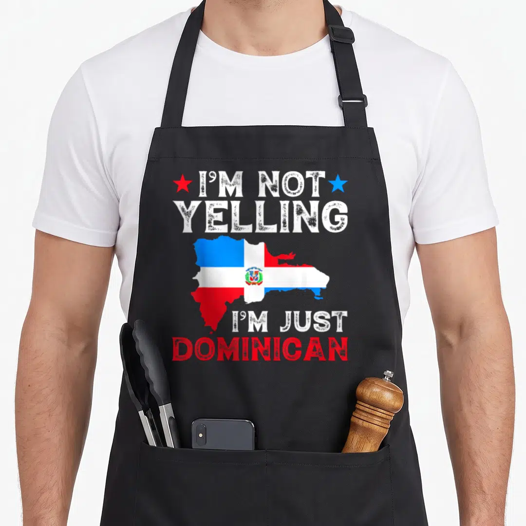 Yelling i love dominican apron - Distressed text I'm Not Yelling I'm Just Dominican over a map of the country in red — shown on a black cotton canvas apron against a white background