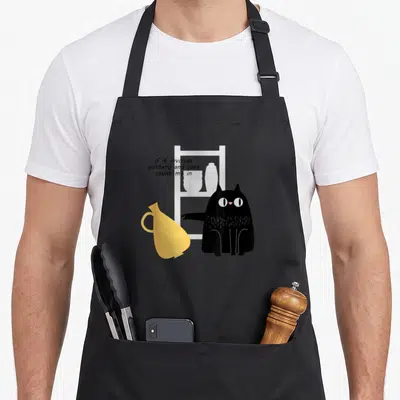 Pottery cat apron - Black cat reaching for yellow vase next to white shelf with text if it involves pottery and cats — shown on a black cotton canvas apron against a white background