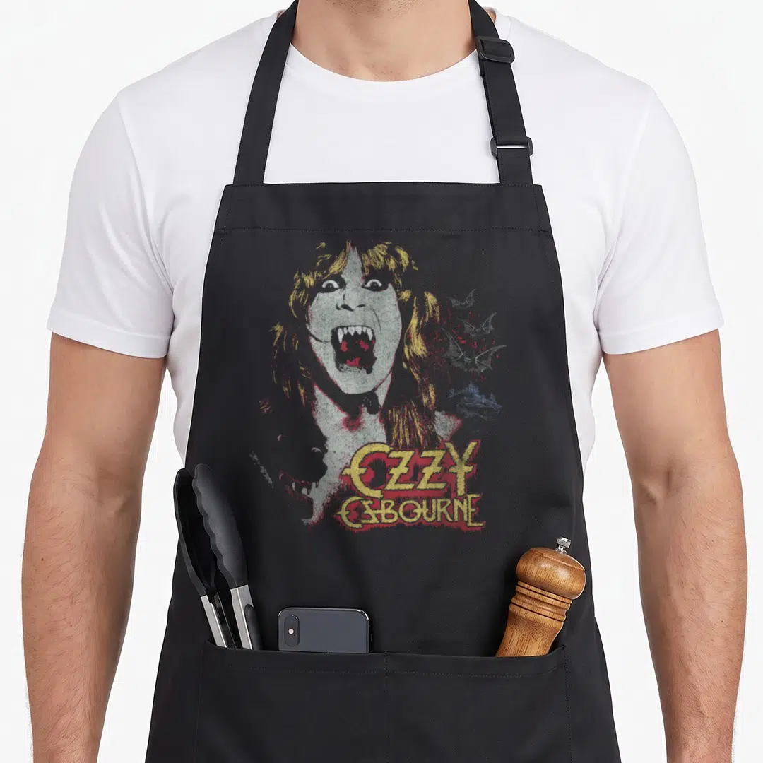 Ozzy devil's apron - Distressed grey vampire portrait with yellow OZZY OSBOURNE text and small red bat silhouettes — shown on a black cotton canvas apron against a white background