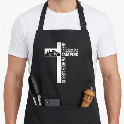 Bit camping apron - White cross with black mountain and tent scene, vertical and horizontal text — shown on a black cotton canvas apron against a white background