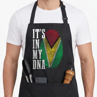 Guyanese pride apron - Vertical IT'S IN MY DNA text beside green yellow red fingerprint with distressed texture — shown on a black cotton canvas apron against a white background