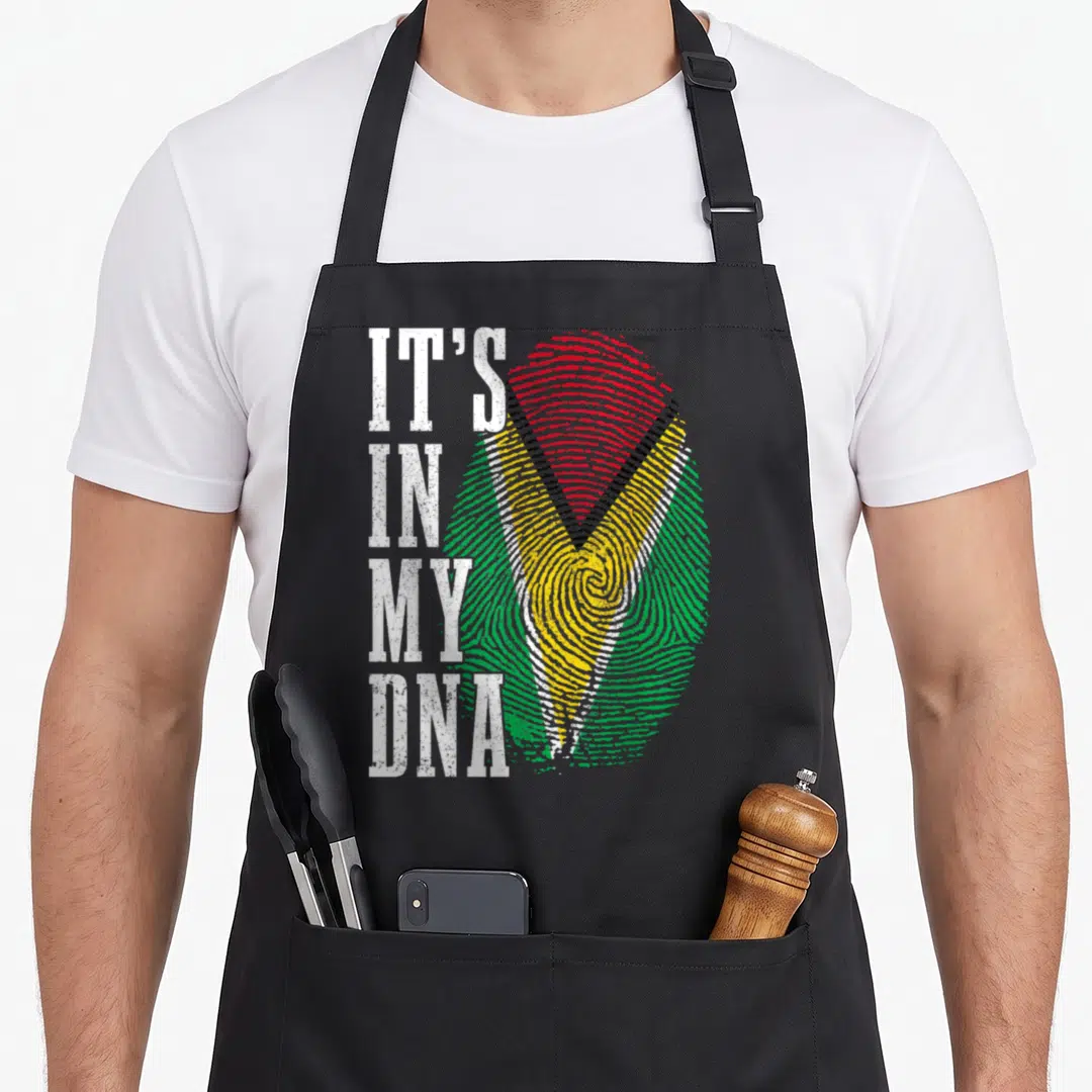 Guyanese pride apron - Vertical IT'S IN MY DNA text beside green yellow red fingerprint with distressed texture — shown on a black cotton canvas apron against a white background