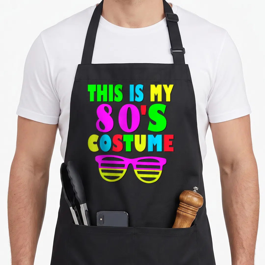 80s 70s apron - Multicolored text THIS IS MY 80'S COSTUME above magenta and yellow shutter shades — shown on a black cotton canvas apron against a white background