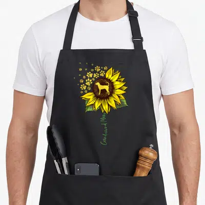 Coonhound dog mom apron - Yellow sunflower with dog silhouette and vertical greyhound mom text stem — shown on a black cotton canvas apron against a white background