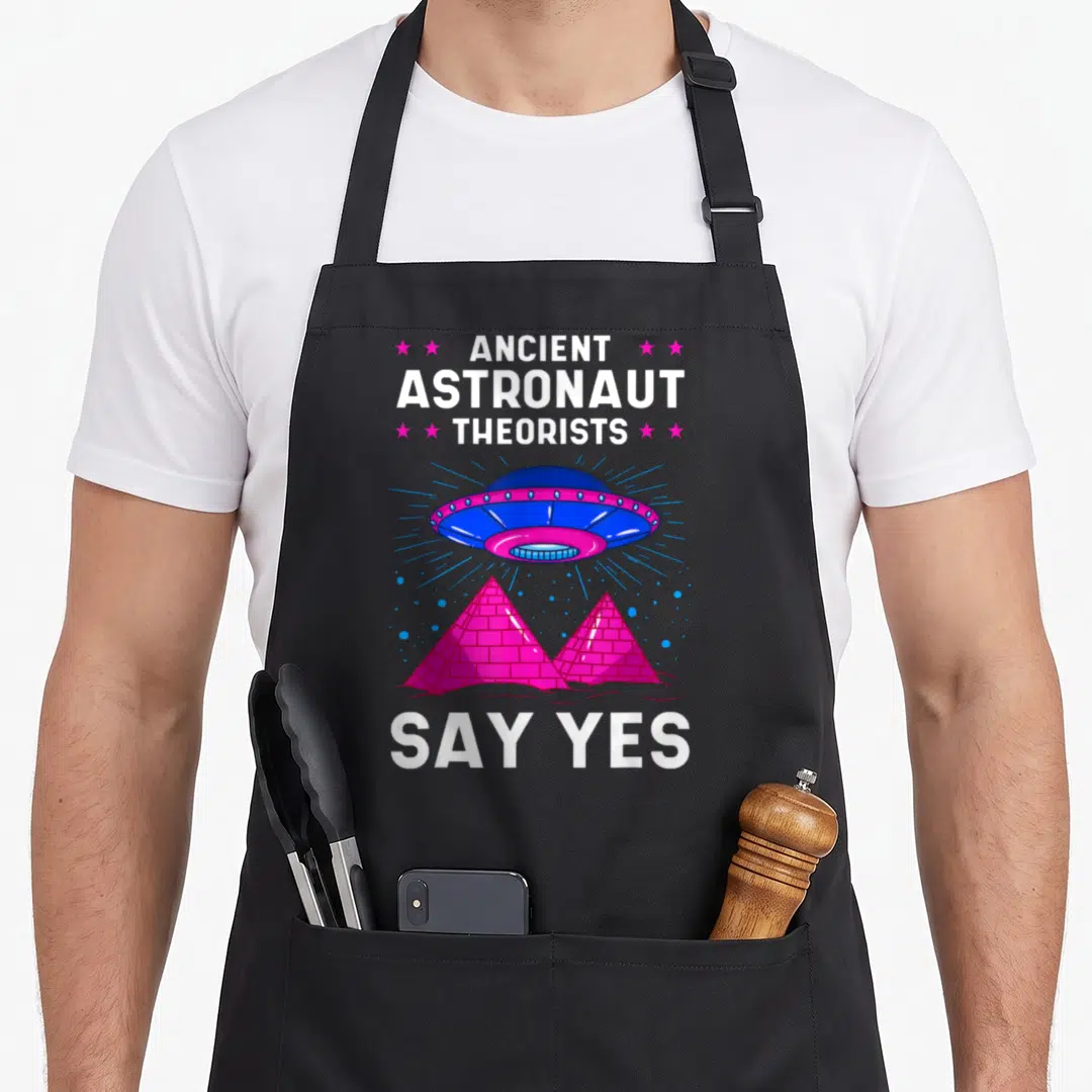 Astronaut ancient egyptian apron - UFO floating above two pink pyramids withAncient Astronaut Theorists Say Yes text — shown on a black cotton canvas apron against a white background