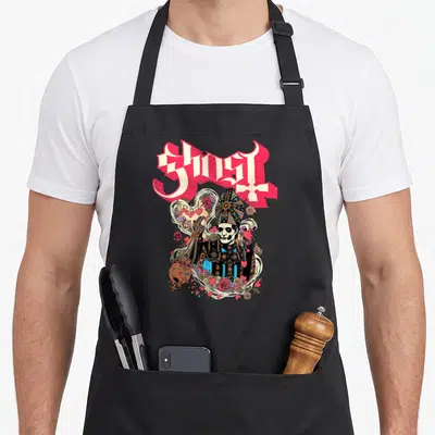 Papa valentine apron - Papa Emeritus figure holding red heart under GHOST text with roses and smoke in pink and black — shown on a black cotton canvas apron against a white background